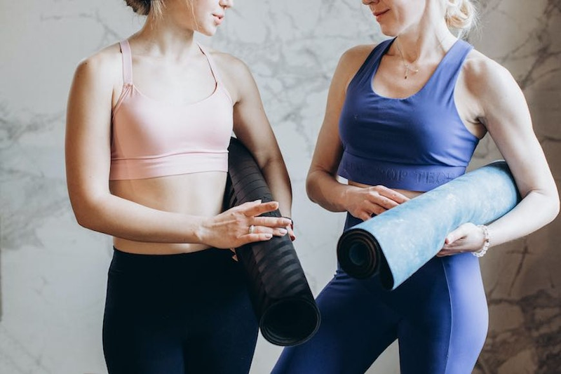 two women holding yoga mats